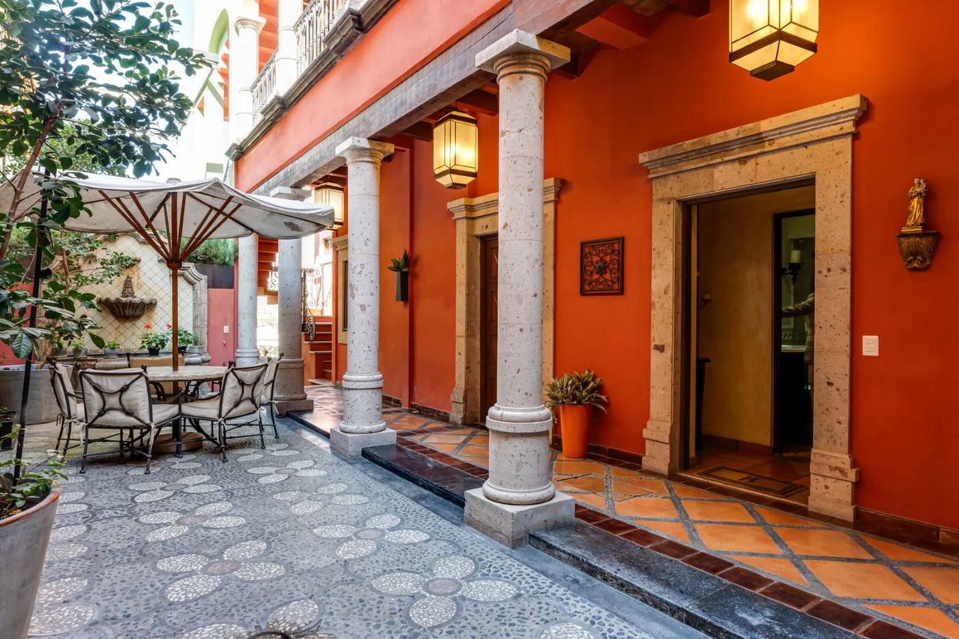 Colonnaded corridor with terracotta walls, iron lanterns and a pebble-mosaic floor