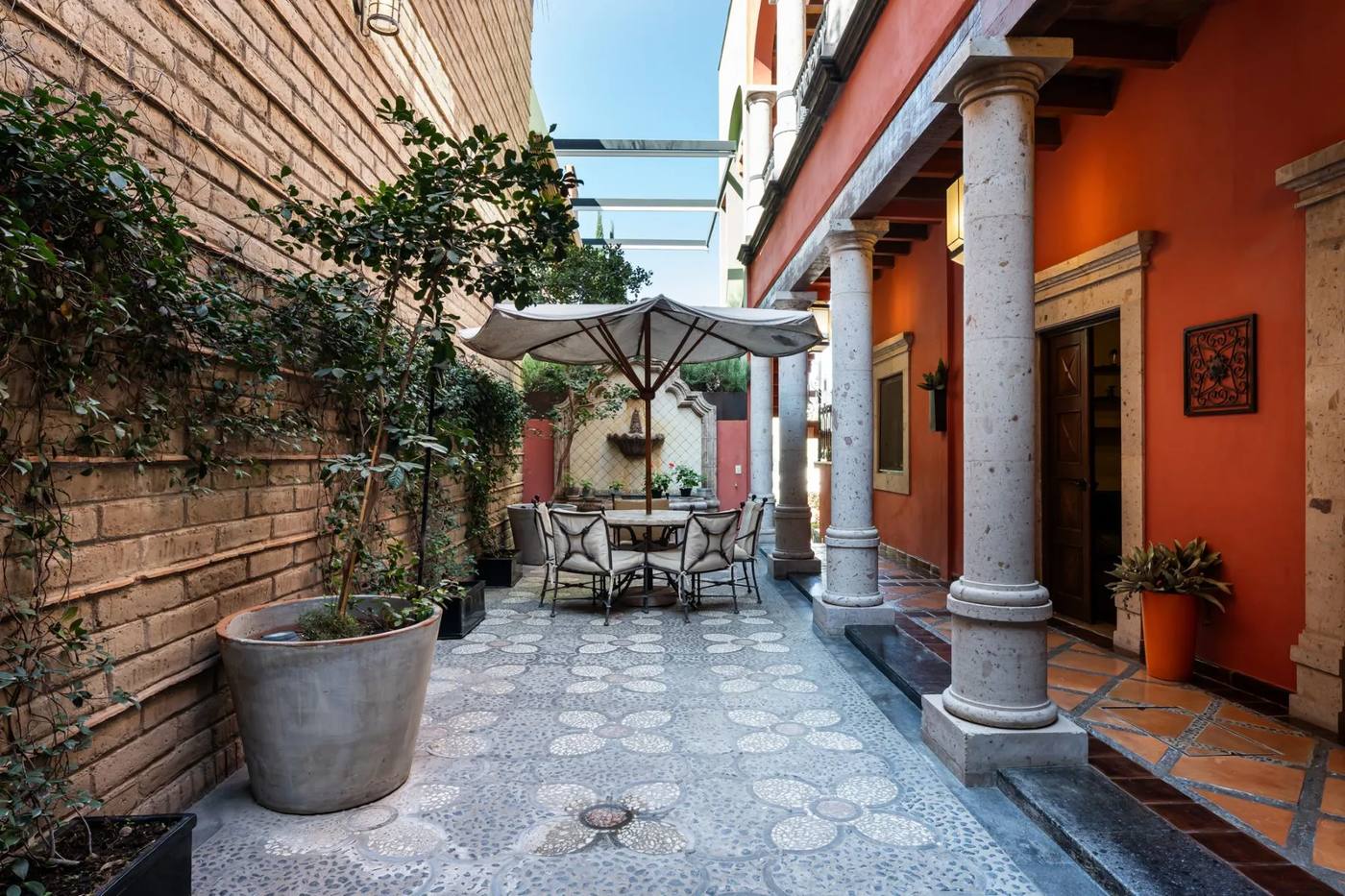 Stone courtyard with a shaded dining table under limestone columns