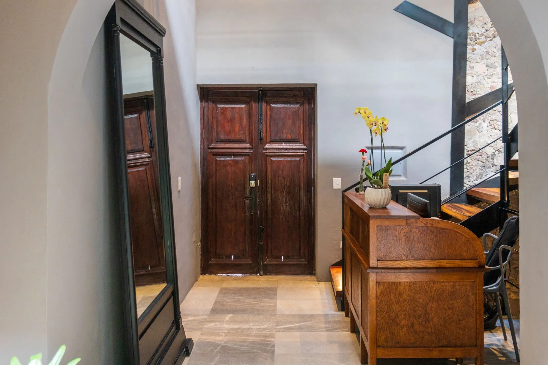 Colonial front hall with tall antique mesquite doors, a full-length mirror and a stone arch