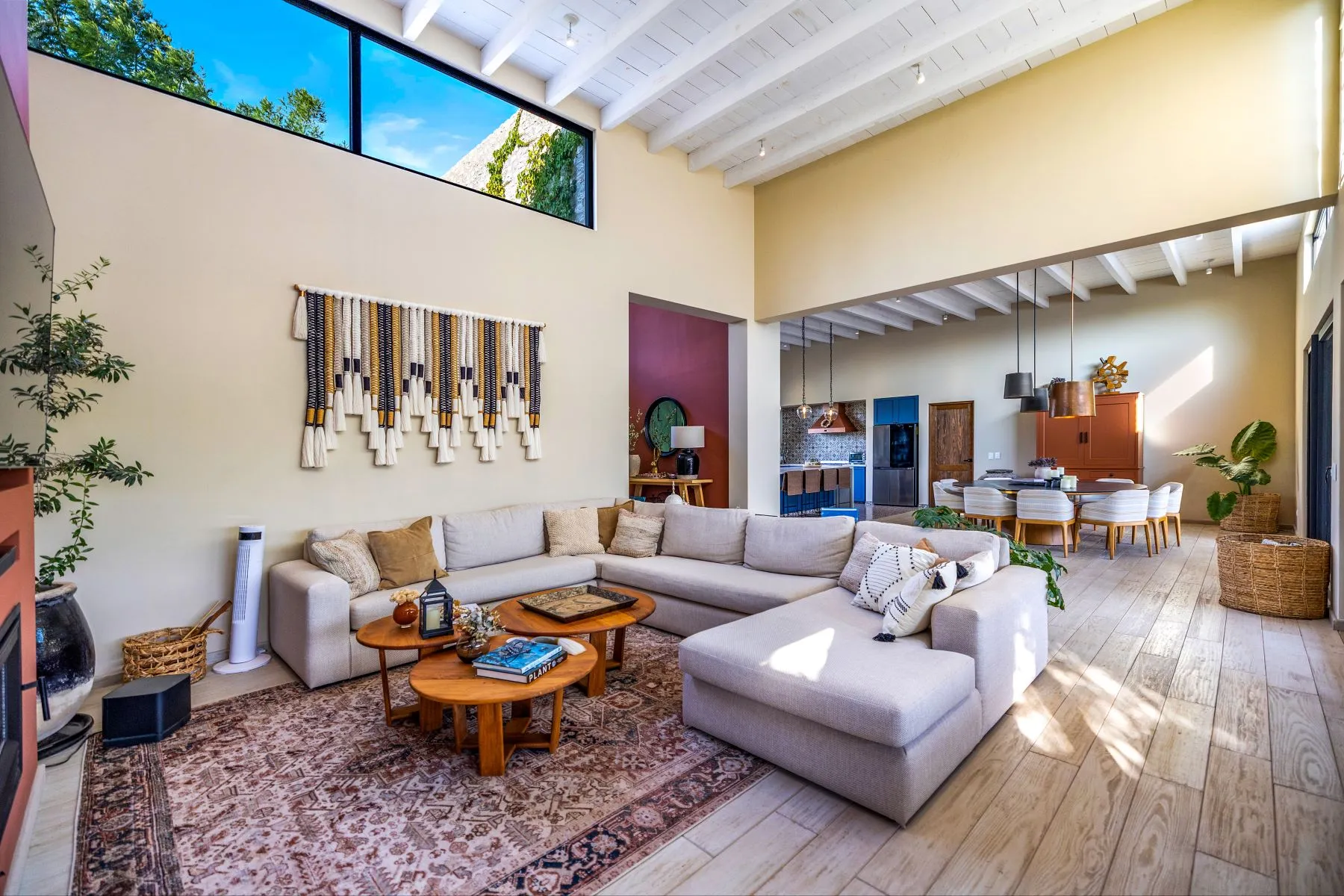 Double-height living room with a sectional sofa, an antique rug and the kitchen beyond