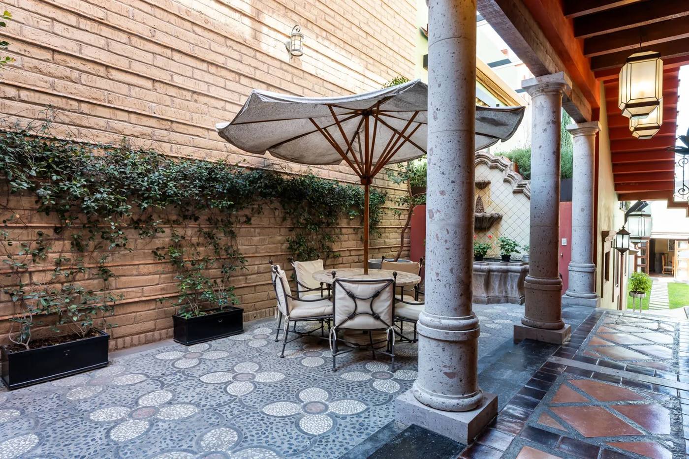 Pebble-mosaic patio with a shaded table between limestone columns